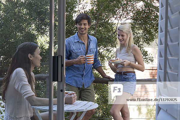Smiling friends with coffee on veranda