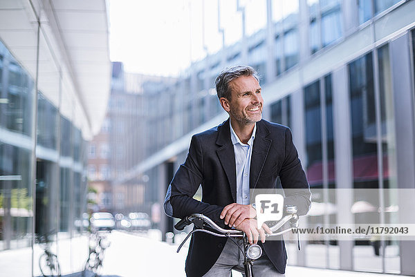 Smiling businessman on bicycle in the city