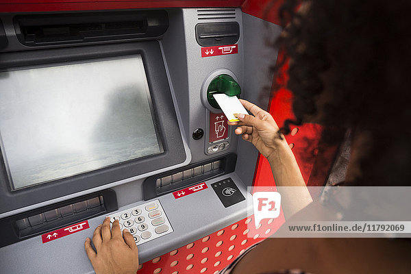 Frau schiebt Kreditkarte am Geldautomaten