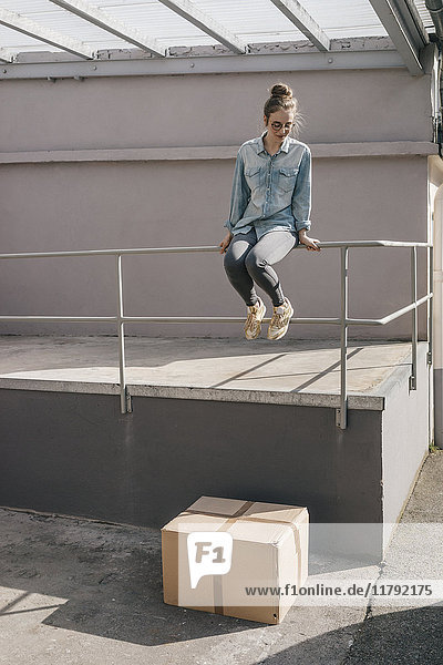 Junge Frau im Begriff  auf Karton zu springen