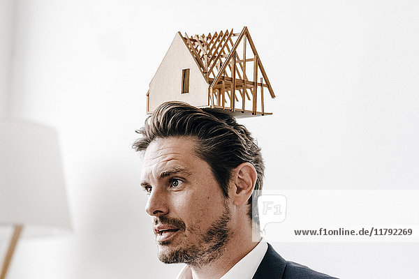 Ein Mann  der ein Architekturmodell auf dem Kopf balanciert.