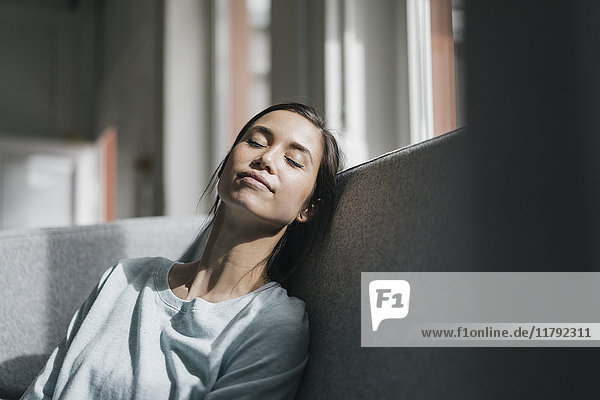 Young woman sitting on couch  taking a nap