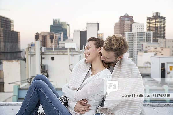 Romantic couple sitting on rooftop terrace  enjoying the view
