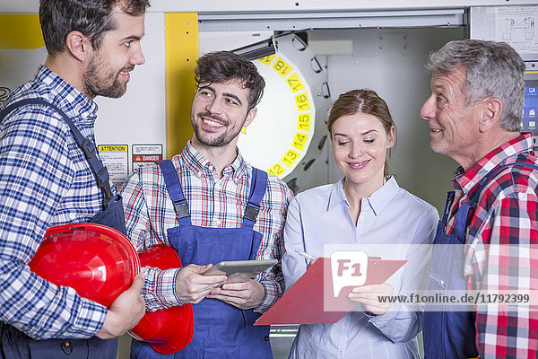 Lächelndes Personal in der Fabrik mit CNC-Maschine im Hintergrund