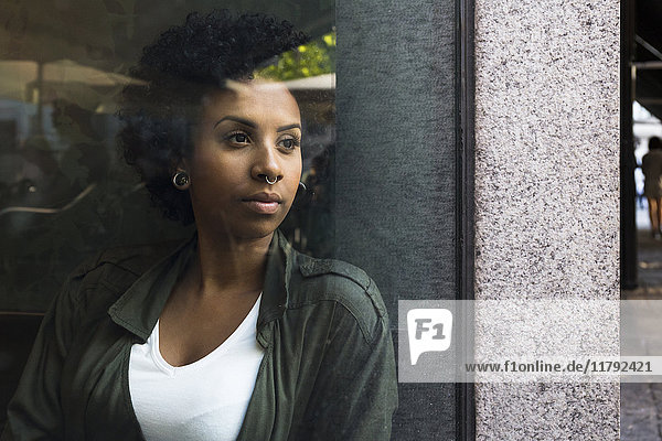Porträt einer jungen Frau  die aus dem Fenster eines Cafés schaut.