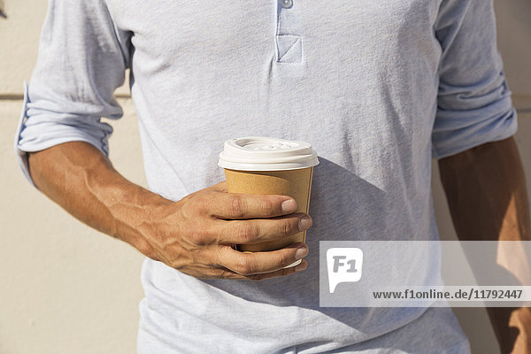 Young man holding cup of take away coffee