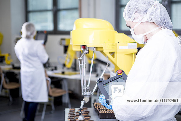 Frau in der Fabrik untersucht Roboter beim Umgang mit Cookies