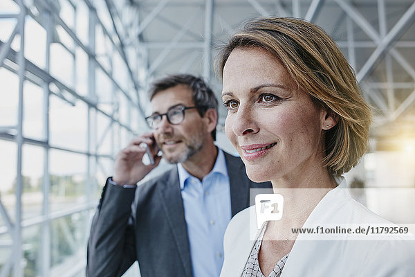 Smiling businesswoman and businessman on cell phone at the airport