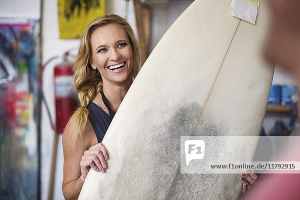 Surfboard Shaper Workshop  Mitarbeiterin lächelt mit Surfboard