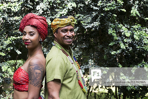 Portrait of father and adult daughter back to back wearing traditional Brazilian clothing