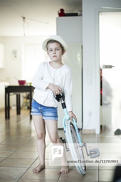 Porträt eines ernsthaften kleinen Mädchens mit Einrad zu Hause