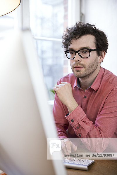 Zuversichtlicher Mann im Büro mit Blick auf den Computerbildschirm