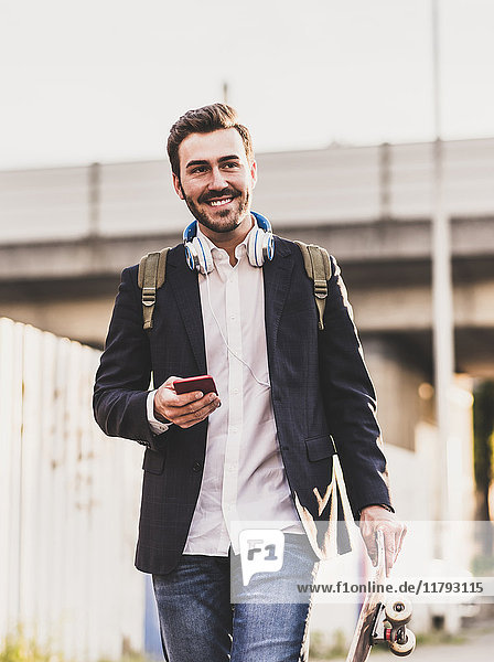 Smiling young man on the move holding cell phone