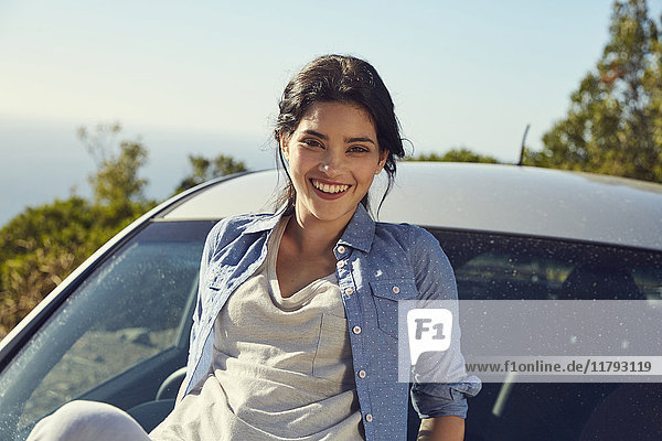 Lächelnde junge Frau an einem Auto