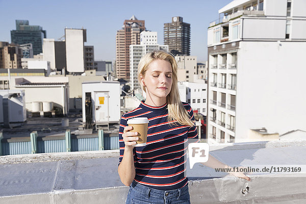 Junge Frau trinkt Kaffee auf der Dachterrasse