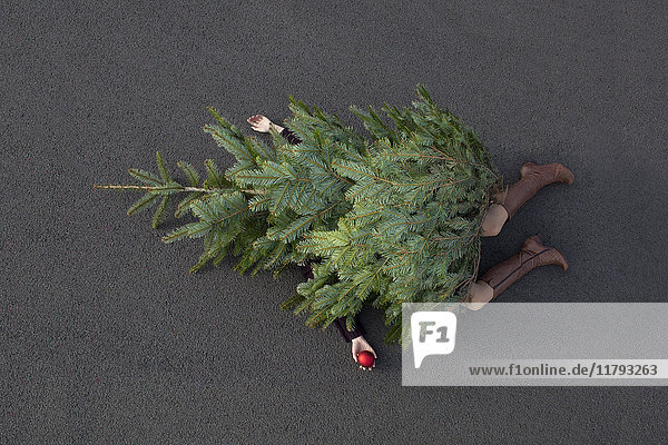 Woman lying buried under Christmas tree