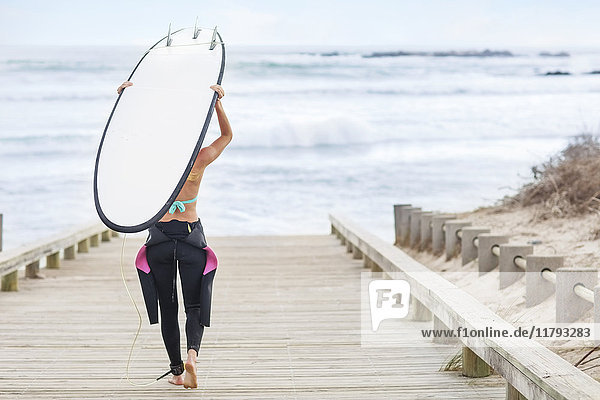 Woman walking to beach with surfboard