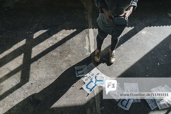 Woman standing on concrete floor using tablet and working on letter templates