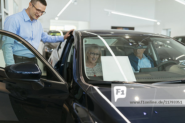 Salesman advising customers in car dealership