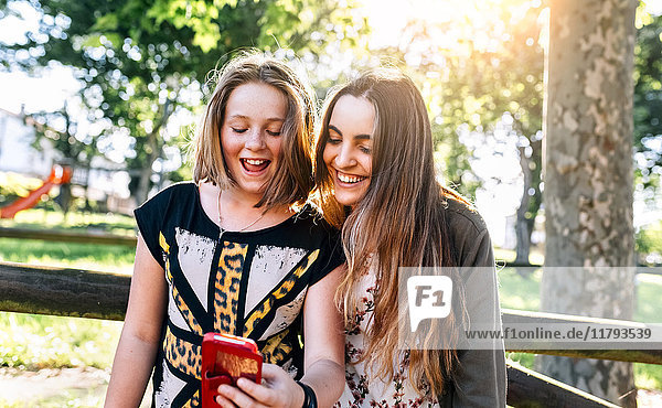 Zwei Mädchen haben Spaß mit ihrem Smartphone im Freien