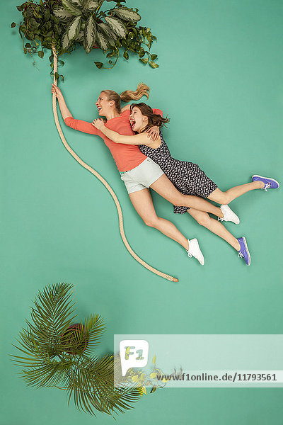 Two women swinging on a liana through the jungle