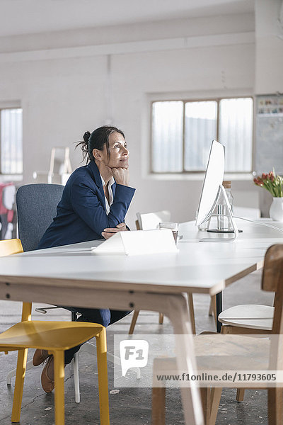 Nachdenkliche Geschäftsfrau sitzt am Schreibtisch in einem Loft