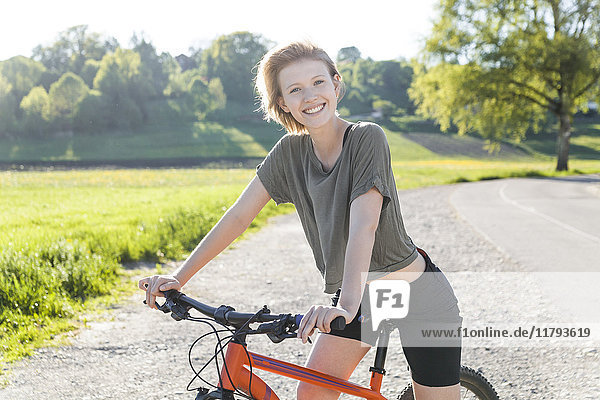 Porträt einer lächelnden jungen Frau mit Mountainbike