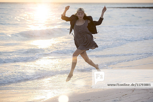 Junge Frau springt vor Freude am Strand