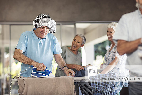 Senioren bügeln Kleidung zusammen Spaß haben
