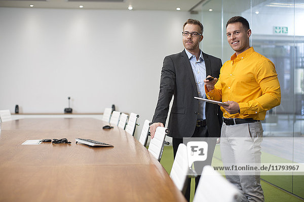 Two businessmen with tablet in office boardroom