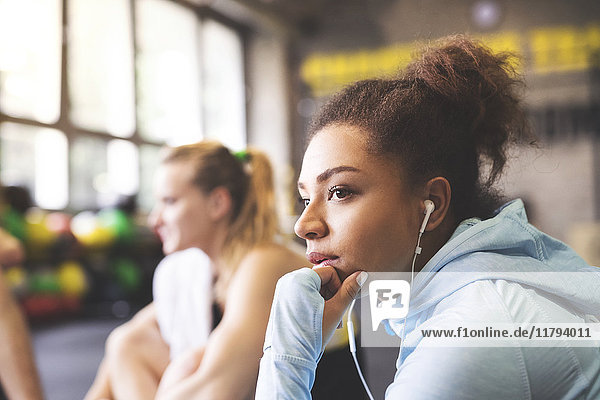 Young woman with earbuds having a break in gym