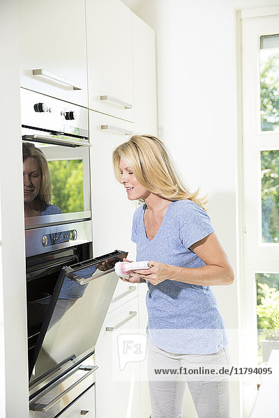 Woman in kitchen closing oven