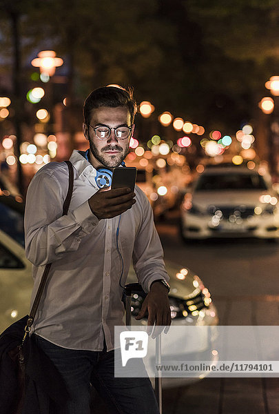 Young man in the city checking cell phone at night