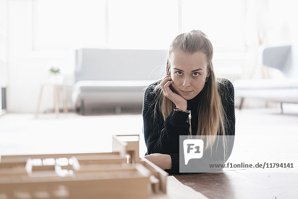 Porträt einer blonden jungen Frau mit Architekturmodell auf dem Tisch