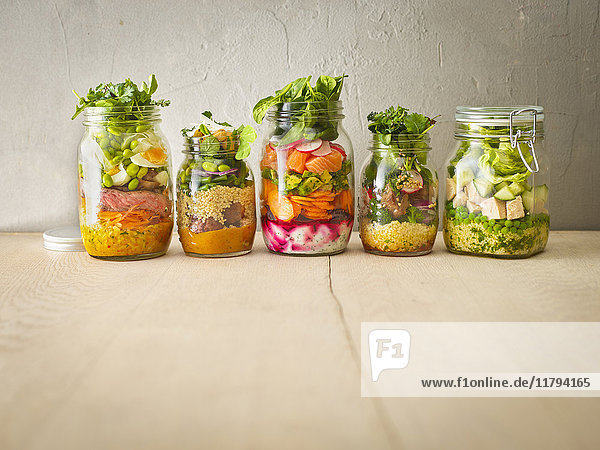 Reihe von fünf Einmachgläsern mit verschiedenen Salaten