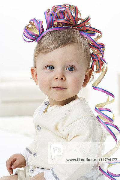 Porträt eines lächelnden Kleinkindes mit Streamer auf dem Kopf