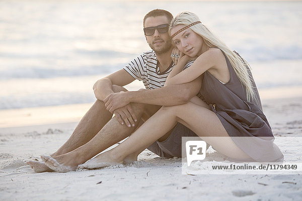 Young couple sitting on the beach  embracing