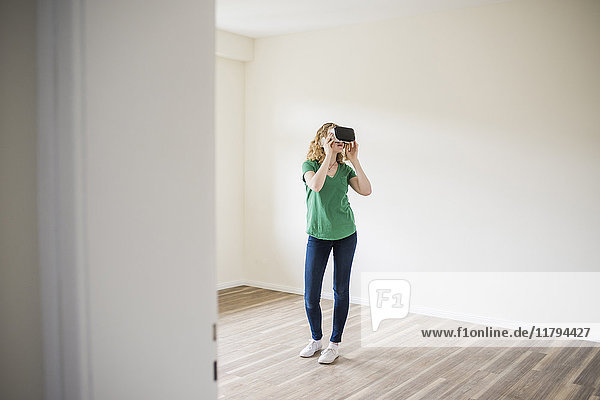 Woman in empty apartment wearing VR glasses