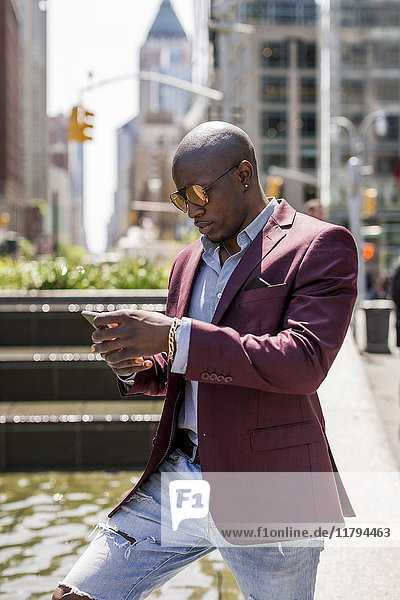 USA  New York City  Manhattan  stilvoller Geschäftsmann mit Blick auf Smartphone