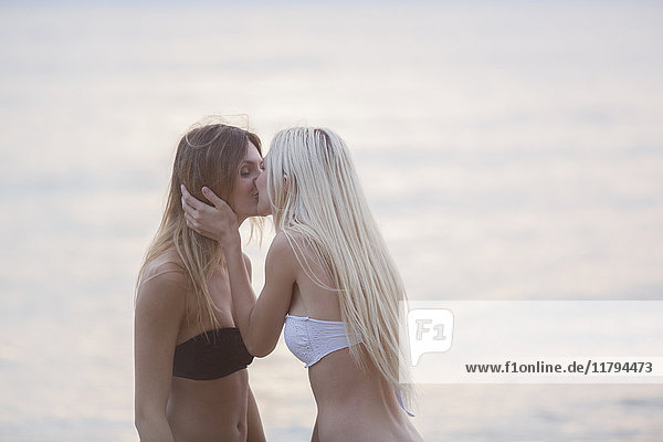 Zwei junge Frauen  die sich am Meer küssen.