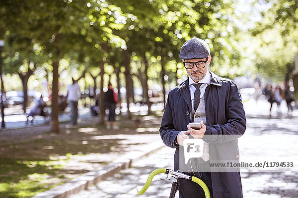 Reife Geschäftsleute mit Fahrrad und Smartphone in der Stadt
