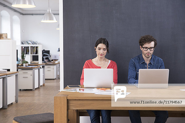 Mann und Frau mit Laptops auf dem Tisch im Büro