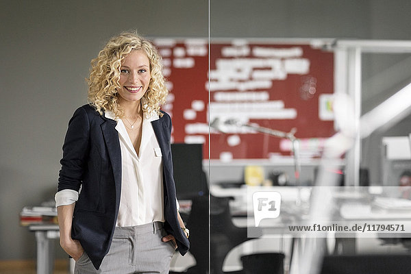 Dynamic businesswoman standing in office  smiling