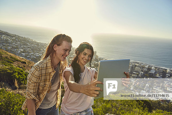 Südafrika  Kapstadt  Signal Hill  zwei junge Frauen über der Stadt  die einen Selfie mit Tablette nehmen.