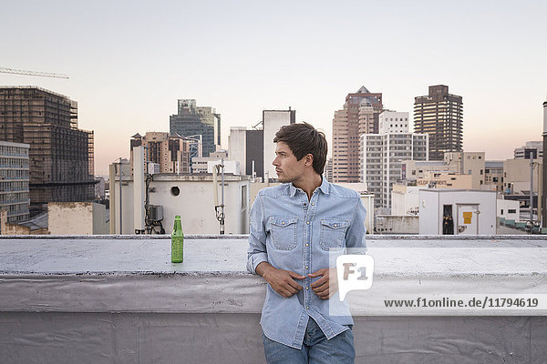 Confident young man standing on a rooftop terrace