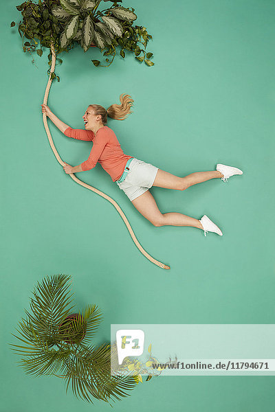 Woman swinging on a liana through the jungle