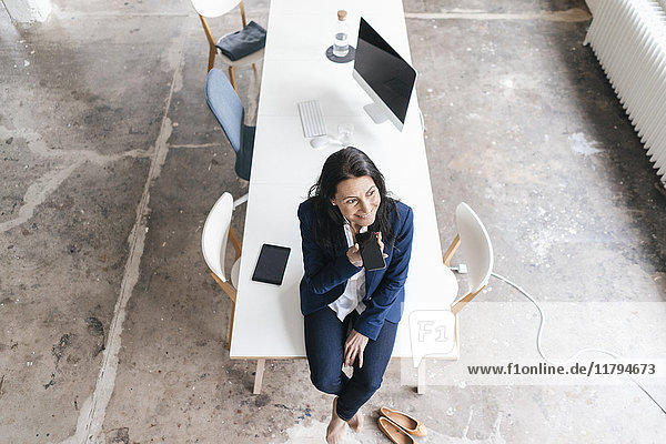 Smiling businesswoman sitting on desk in a loft