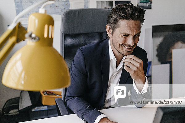 Lächelnder Geschäftsmann bei der Arbeit am Schreibtisch