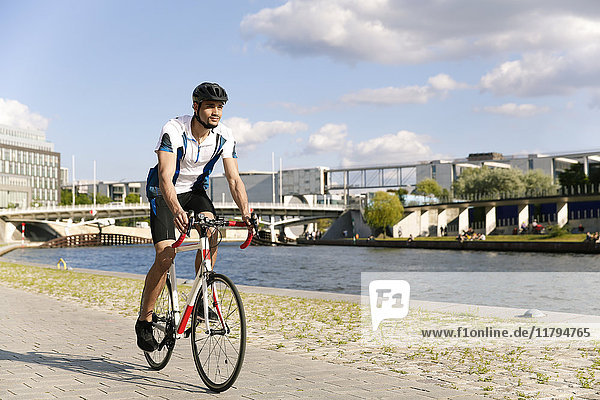 Junger Mann auf dem Fahrrad am Wasser in der Stadt