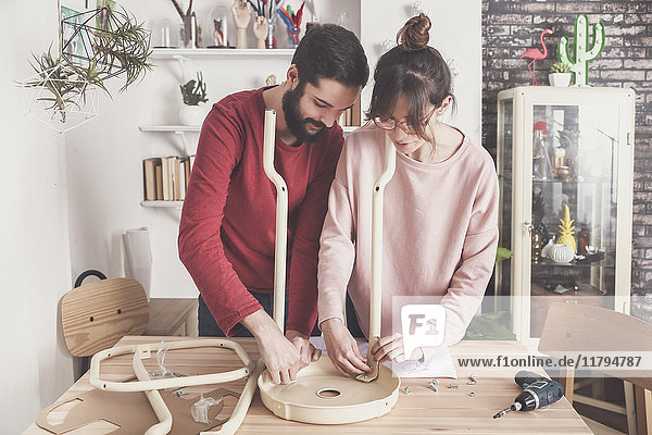 Young couple assembling flat-pack stool at home